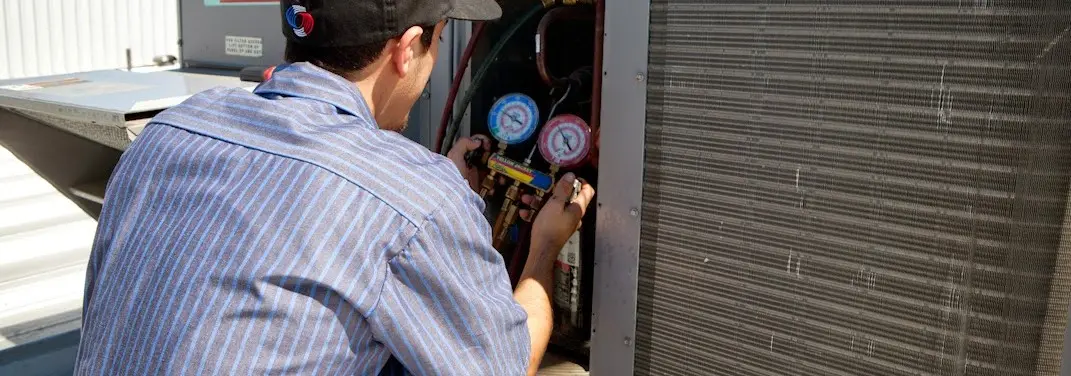 HVAC technician servicing a condenser unit in Wright